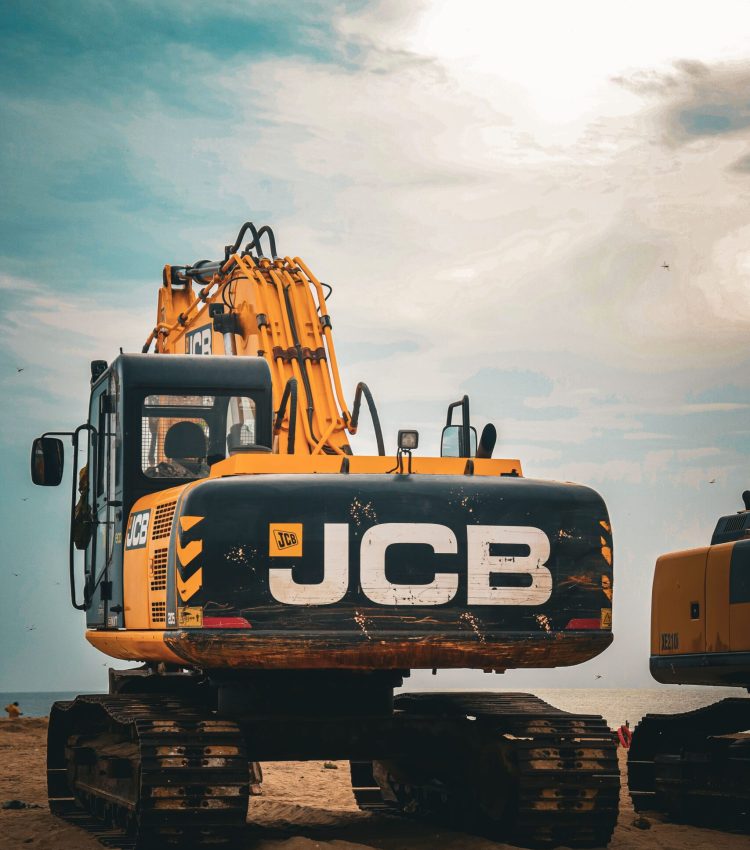 A JCB excavator on a construction site under a cloudy sky.